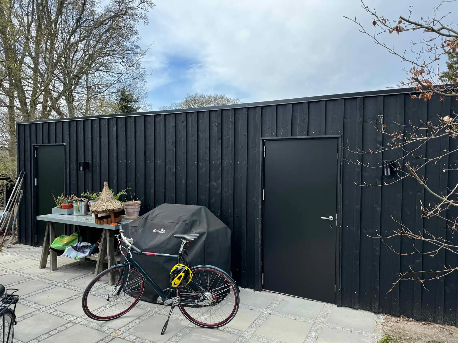 Sortmalet udhus med plads til cykler og havemøbler